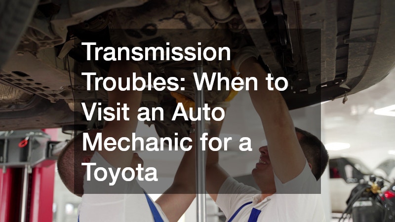 two auto mechanics working underneath a car on a hydraulic lift